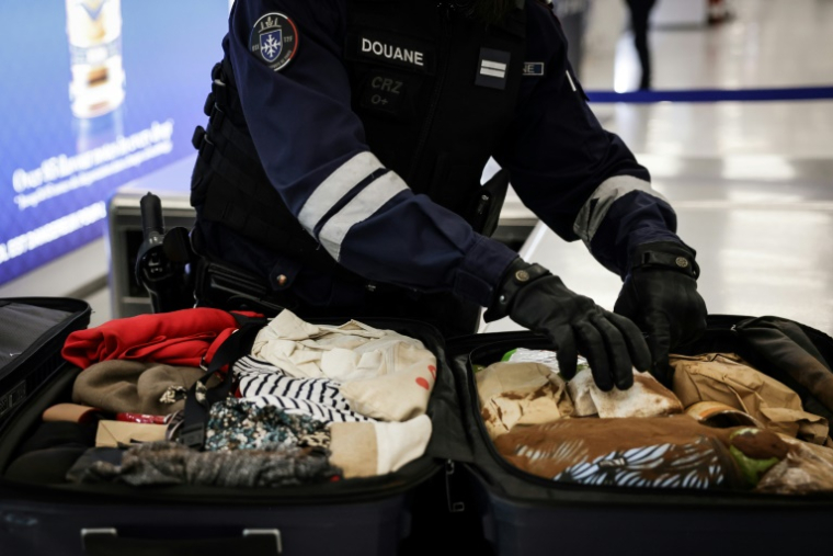 Un douanier inspecte les bagages de passagers à l'aéroport de Roissy-Charles-de-Gaulle, au nord de Paris, le 21 mars 2025 ( AFP / Thibaud MORITZ )