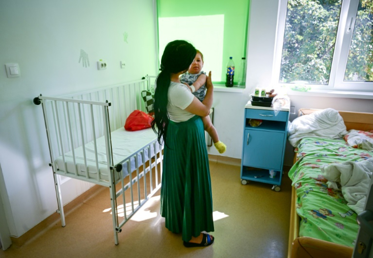 Une jeune mère ne souhaitant pas être identifiée avec son bébé de dix mois ayant peut-être contracté la rougeole, à l'hôpital de Piatra Neamt, en Roumanie, le 23 juin 2025. ( AFP / Daniel MIHAILESCU )