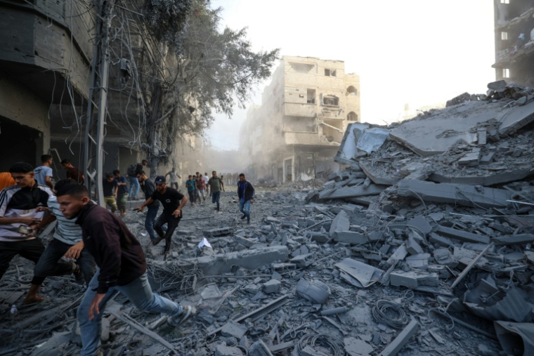 Des personnes courent se mettre à l'abri après une frappe israélienne qui a visé un bâtiment dans le camp de réfugiés palestiniens de Bureij, dans le centre de la bande de Gaza, le 19 octobre 2025 ( AFP / Eyad BABA )