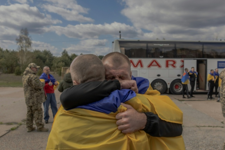 Des prisonniers de guerre ukrainiens libérés par la Russie dans le cadre d'un échange, enveloppés dans le drapeau ukrainien, dans un lieu non dévoilé de la région de Tcherniguiv, le 24 avril 2026  ( AFP / Roman PILIPEY )