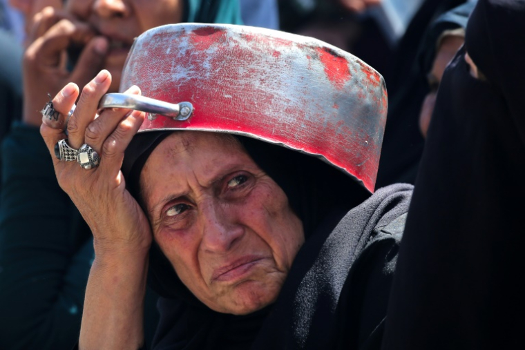 Une Palestinienne fait la queue pour recevoir un repas chaud à un point de distribution de nourriture dans le camp de réfugiés de Nousseirat, dans le centre de la bande de Gaza, le 24 mai 2025 ( AFP / Eyad BABA )