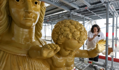 La restauratrice d'art Cyrielle D'Antoni travaille avec des feuilles d'or sur la statue de Jésus, à côté de la Vierge Marie, lors de la rénovation de la basilique Notre-Dame de la Garde à Marseille, le 3 septembre 2025 ( AFP / Miguel MEDINA )
