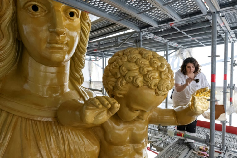 La restauratrice d'art Cyrielle D'Antoni travaille avec des feuilles d'or sur la statue de Jésus, à côté de la Vierge Marie, lors de la rénovation de la basilique Notre-Dame de la Garde à Marseille, le 3 septembre 2025 ( AFP / Miguel MEDINA )