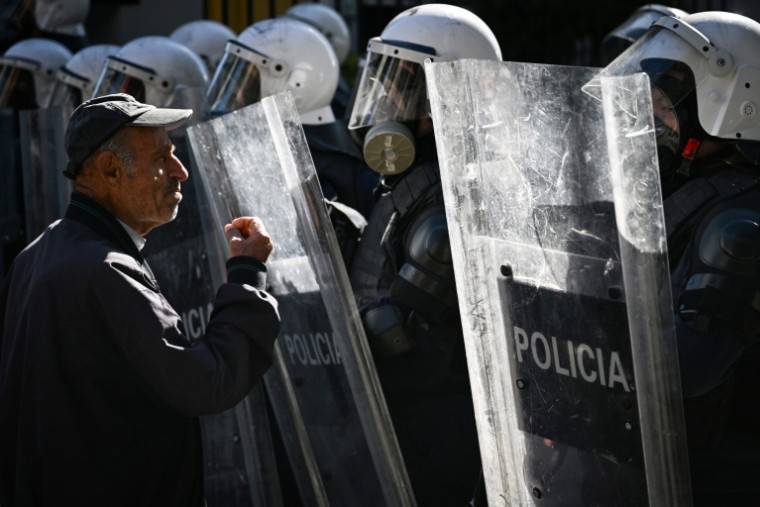 Un manifestant fait face à des policiers anti-émeutes lors d'une manifestation contre le gouvernement dans le centre de Tirana, le 16 octobre 2026 ( AFP / Armend NIMANI )
