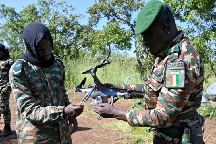 Des gardes-forestiers de l'Office ivoirien des Parcs et Réserves (OIPR) préparent le lancement d'un drone de surveillance dans le parc national de la Comoè, dans le nord-est de la Côte d'Ivoire le 10 octobre 2025. ( AFP / Issouf SANOGO )