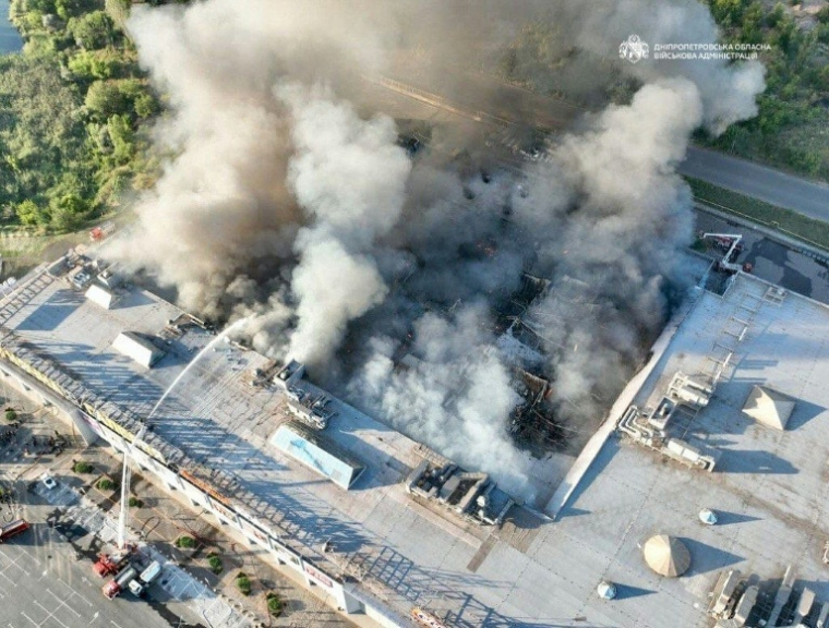 Photo diffusée par l'administration militaire régionale de Dnipropetrovsk, le 21 août 2026, montrant des pompiers luttant contre un incendie sur le site d'un centre commercial endommagé par une frappe russe à Kryvyï Rig, en Ukraine ( Administration militaire régionale de Dnipropetrovsk / Handout )