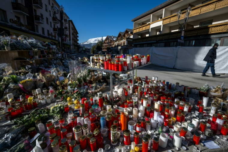 Un homme passe devant un mémorial aux victimes de l'incendie du bar Constellation, à Crans-Montana en Suisse le 6 janvier 2026 ( AFP / Fabrice COFFRINI )