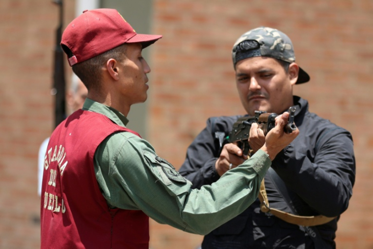 Un Vénézuélien reçoit des explications sur le maniement d'un fusil lors d'un entraînement militaire à Fort Tiuna à Caracas, le 20 septembre 2025 ( AFP / Pedro MATTEY )