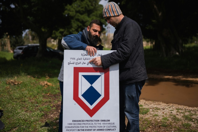 Des employés installent un panneau de l'Unesco sur le site de l'hippodrome romain de Tyr, dans le sud du Liban, le 23 mars 2026 ( AFP / Dimitar DILKOFF )