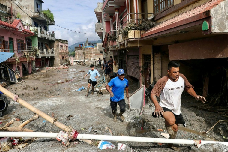 Des habitants passent devant des maisons noyées sous la boue après des crues soudaines à Devighat au Népal, le 27 août 2026 ( AFP / Prabin RANABHAT )