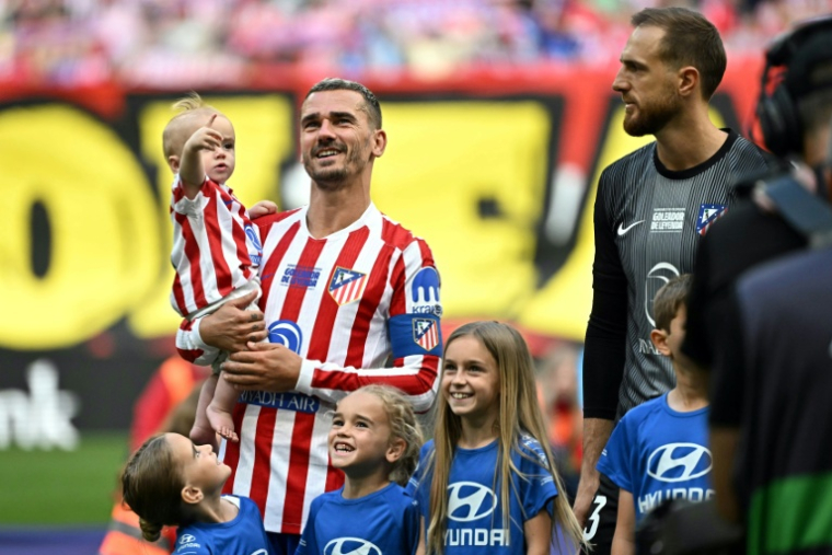 L'attaquant français de l'Atlético Madrid Antoine Griezmann porte sa fille Shai avant le début du match de Liga contre Gérone, le 17 mai 2026 au Metroplitano ( AFP / Javier SORIANO )