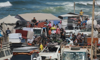 Des Palestiniens transportant leurs effets personnels traversent une route côtière au nord-ouest de Nousseirat (centre) après leur fuite de Gaza-ville, le 1er octobre 2025 ( AFP / Bashar TALEB )