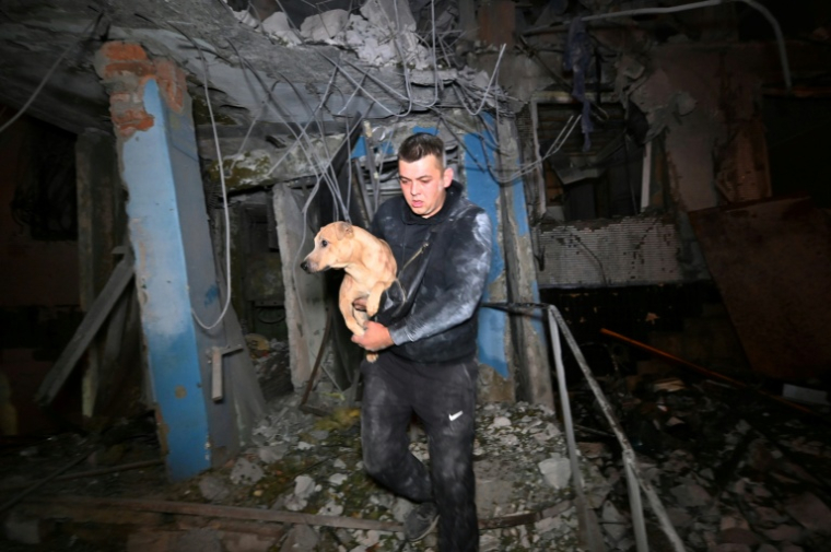 Un habitant évacue son chien d'un immeuble résidentiel à plusieurs étages, endommagé à la suite d'une frappe aérienne russe sur Kharkiv le 28 septembre 2026. ( AFP / SERGEY BOBOK )