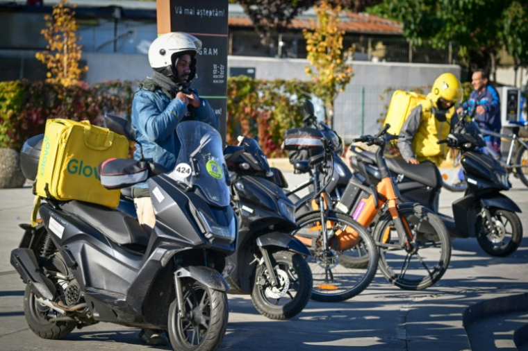 Des livreurs étrangers attendent des commandes devant l'aire de restauration d'un centre commercial à Bucarest, le 10 octobre 2025 en Roumanie ( AFP / Daniel MIHAILESCU )