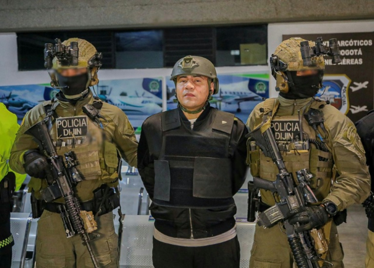 Photo retouchée à la source pour dissimuler l'identité des agents, diffusée par le service de presse de la Police nationale colombienne, montrant Andres Felipe Marin Silva, dit "Pipe Tulua", escorté avant son extradition vers les États-Unis à Bogota le 3 février 2026 ( Colombian National Police / PRENSA POLICIA NACIONAL )
