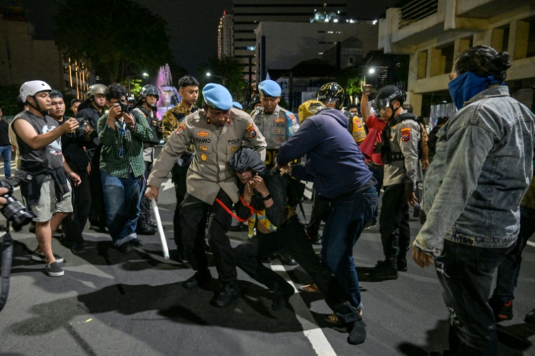 Des policiers arrêtent un manifestant lors d'un rassemblement contre la hausse du prix des carburants non subventionné et le programme phare de repas gratuits du président Prabowo, le 26 juin 2026 à Surabaya, en Indonésie ( AFP / Juni KRISWANTO )