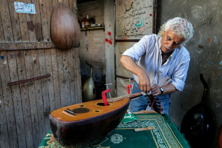 Le luthier palestinien Souhail Abou Chawich dans son atelier de réparation d'ouds, au camp de réfugiés de Nousseirat, dans le centre de la bande de Gaza, le 23 juin 2026 ( AFP / Eyad Baba )
