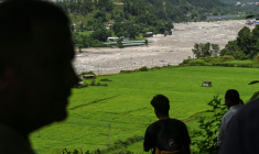 Des habitants regardent la rivière Trishuli alors qu’ils se réfugient sur un terrain surélevé après une alerte aux inondations dans la région de Pipaltar, dans le district de Nuwakot au Népal, le 28 août 2026 ( AFP / Arun SANKAR )