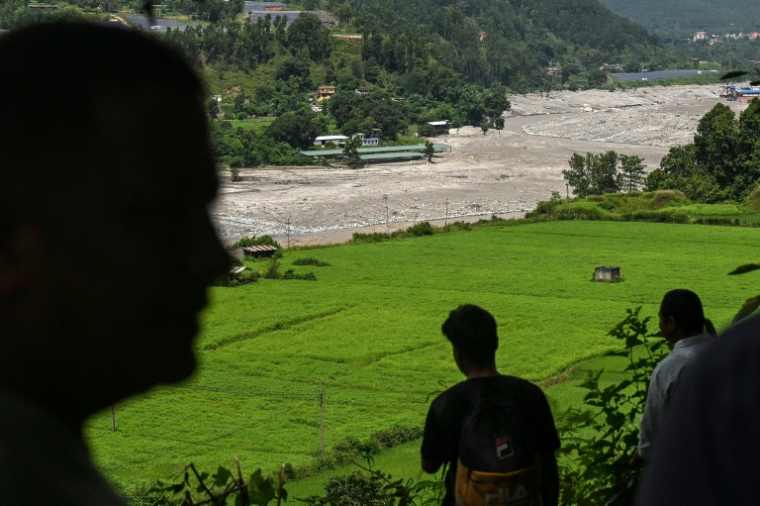 Des habitants regardent la rivière Trishuli alors qu’ils se réfugient sur un terrain surélevé après une alerte aux inondations dans la région de Pipaltar, dans le district de Nuwakot au Népal, le 28 août 2026 ( AFP / Arun SANKAR )