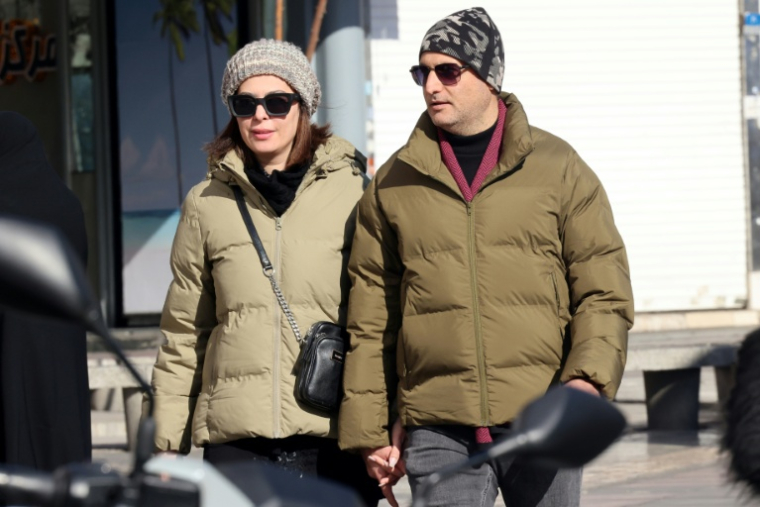 Un couple marche dans les rues de Téhéran, où les autorités ont fermé écoles, banques et établissements publics en raison du froid et pour économiser l'énergie, le 31 décembre 2025 ( AFP / ATTA KENARE )