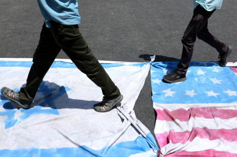 De Iraniens piétinent les draêux américain et israélien lors d'une manifestation à Téhéran, le 20 juin 2025 ( AFP / - )