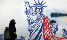 Cette photo, prise le 26 février 2026, montre une Iranienne voilée passant devant une fresque anti-américaine située à côté de l'ancienne ambassade des États-Unis à Téhéran. ( AFP / - )