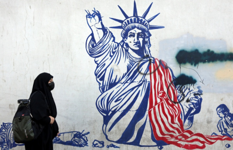 Cette photo, prise le 26 février 2026, montre une Iranienne voilée passant devant une fresque anti-américaine située à côté de l'ancienne ambassade des États-Unis à Téhéran. ( AFP / - )