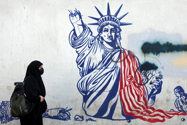 Cette photo, prise le 26 février 2026, montre une Iranienne voilée passant devant une fresque anti-américaine située à côté de l'ancienne ambassade des États-Unis à Téhéran. ( AFP / - )