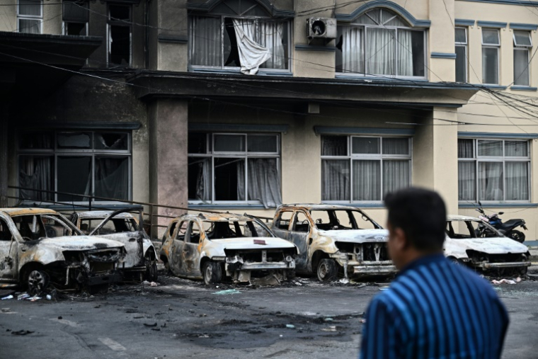Un habitant passe devant des voitures calcinées pendant un couvre-feu à Katmandou, le 12 septembre 2025 au Népal ( AFP / Pedro Pardo )