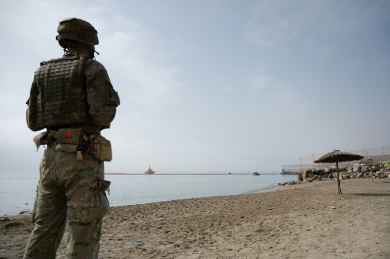 Un militaire espagnol en faction sur une plage alors que la Garde civile espagnole déploie en mer une barrière pneumatique pour empêcher de nouvelles  entrées illégales depuis le Maroc dans l'enclave espagnole de Ceuta, sur la côte nord du Maroc, le 1er août 2026   ( AFP / JORGE GUERRERO )