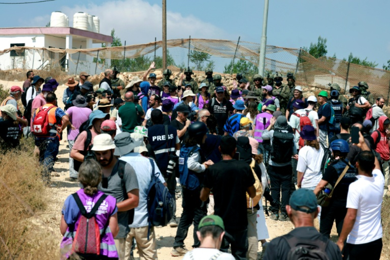 Des Palestiniens et des militants rassemblés pour manifester contre des colons israéliens qui assiègent la maison d'une famille palestinienne dans le village de Qusra, au sud de la ville de Naplouse, en Cisjordanie occupée, le 14 août 2026 ( AFP / Jaafar ASHTIYEH )