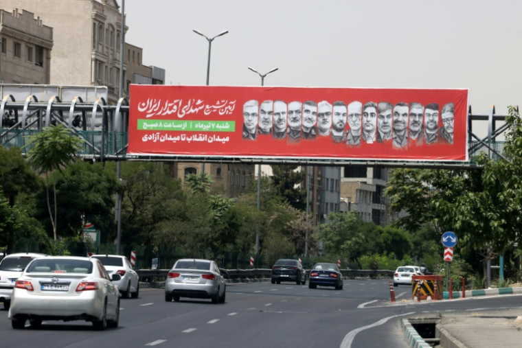 Une banderole avec les portraits de responsables militaires iraniens tués pendant la récente guerre avec Israël appelle à participer à une procession funéraire prévue le 28 juin, le 26 juin 2025 à Téhéran ( AFP / ATTA KENARE )