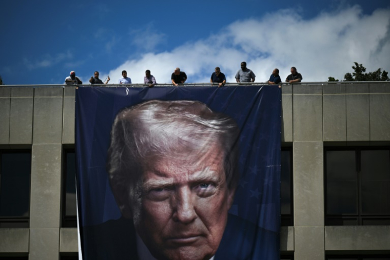 Des ouvriers installent un portrait géant du président américain Donald Trump sur la façade du ministère du Travail à Washington, le 27 août 2025 ( AFP / Drew ANGERER )