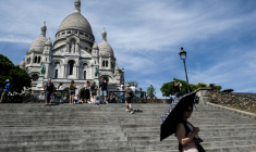 Une touriste se protège du soleil avec un parapluie devant la basilique du Sacré-Cœur à Paris, le 6 juillet 2026, lors d'une vague de chaleur en France ( AFP / Blanca CRUZ )