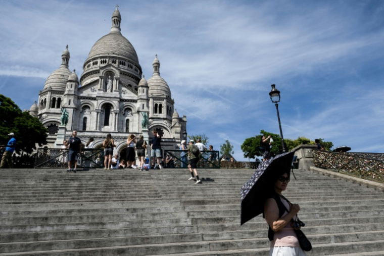 Une touriste se protège du soleil avec un parapluie devant la basilique du Sacré-Cœur à Paris, le 6 juillet 2026, lors d'une vague de chaleur en France ( AFP / Blanca CRUZ )