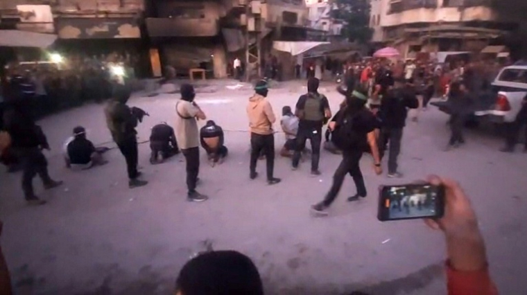 Capture d'écran publiée le 13 octobre 2025 par la chaîne Telegram al-Aqsa contrôlée par le Hamas, montrant des combattants du Hamas debout devant des hommes à genoux et aux yeux bandés, dans une rue de la ville de Gaza ( Al-Aqsa TV / - )