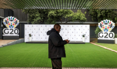 Un délégué passe devant des logos du G20 au centre d'exposition Nasrec à Johannesburg (Afrique du Sud), le 21 novembre 2025 ( AFP / GIANLUIGI GUERCIA )