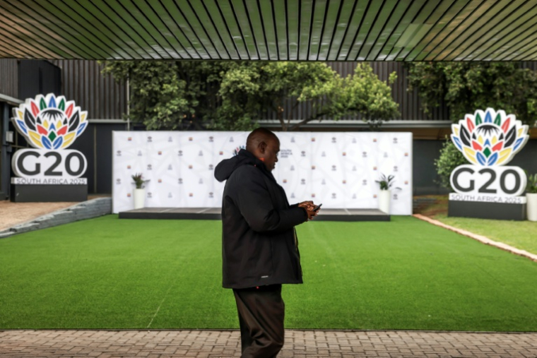Un délégué passe devant des logos du G20 au centre d'exposition Nasrec à Johannesburg (Afrique du Sud), le 21 novembre 2025 ( AFP / GIANLUIGI GUERCIA )