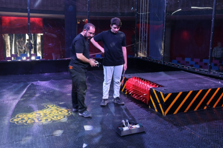 Des étudiants iraniens préparent leur robot avant un combat lors de la deuxième édition des Olympiades de la Tech au parc technologique de Pardis en Iran, en périphérie de Téhéran, le 28 octobre 2025 ( AFP / ATTA KENARE )