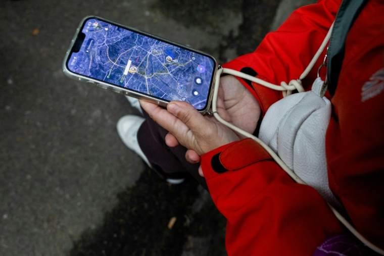 Anastassiia Jmoutska suit les déplacements de son fils Orest sur une carte affichée sur son smartphone, le 13 octobre 2026 à Kiev, en Ukraine ( AFP / Tetiana DZHAFAROVA )
