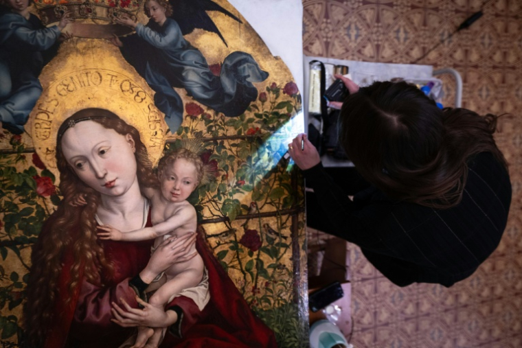 Une experte travaille à la restauration de  "La Vierge au buisson de roses" peint en 1473 par Martin Schongauer, le 5 mars 2026 dans l'église des Dominicains à Colmar, dans le Haut-Rhin ( AFP / SEBASTIEN BOZON )