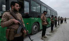Des membres des forces gouvernementales syriennes surveillent un autobus transportant des combattants kurdes, le 10 janvier 2026 à Alep ( AFP / Bakr ALkasem )