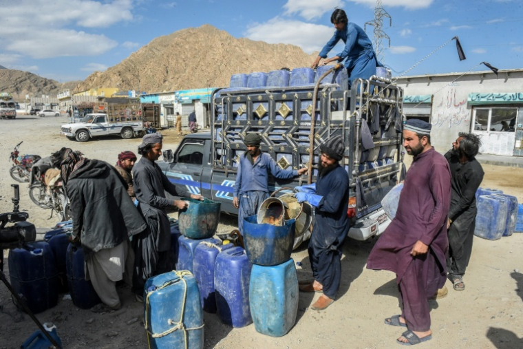 Des vendeurs remplissent des bidons d'essence iranienne de contrebande, à la périphérie de Quetta, dans la province du Baloutchistan, le 14 mar 2026 au Pakistan ( AFP / Banaras KHAN )
