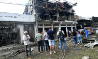 Des passants devant les dégâts provoqués par l'explosion d'une voiture piégée à Corinto, en Colombie, le 10 juin 2025 ( AFP / JOAQUIN SARMIENTO )