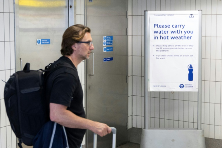 Un homme passe devant un panneau conseillant aux voyageurs d'emporter une bouteille d'eau avec eux, à la gare de Hammersmith, dans l'ouest de Londres, le 22 juin 2026 ( AFP / Brook Mitchell )