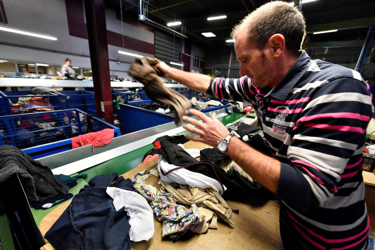 Un homme trie des vêtements dans un centre de recyclage Le Relais à Bordeaux, le 23 janvier 2019. ( AFP / GEORGES GOBET )