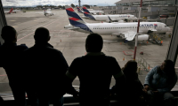Des passagers vénézuéliens regardent des avions de la compagnie LATAM après l'annulation de leur vol pour Caracas, le 19 mai 2025 à l'aéroport El Dorado de Bogota ( AFP / Raul ARBOLEDA )