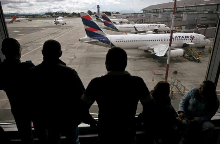 Des passagers vénézuéliens regardent des avions de la compagnie LATAM après l'annulation de leur vol pour Caracas, le 19 mai 2025 à l'aéroport El Dorado de Bogota ( AFP / Raul ARBOLEDA )