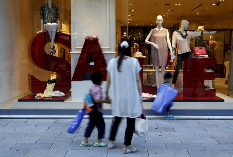 Une femme et ses enfants passent devant la vitrine d'un magasin de marques de luxe à Tokyo