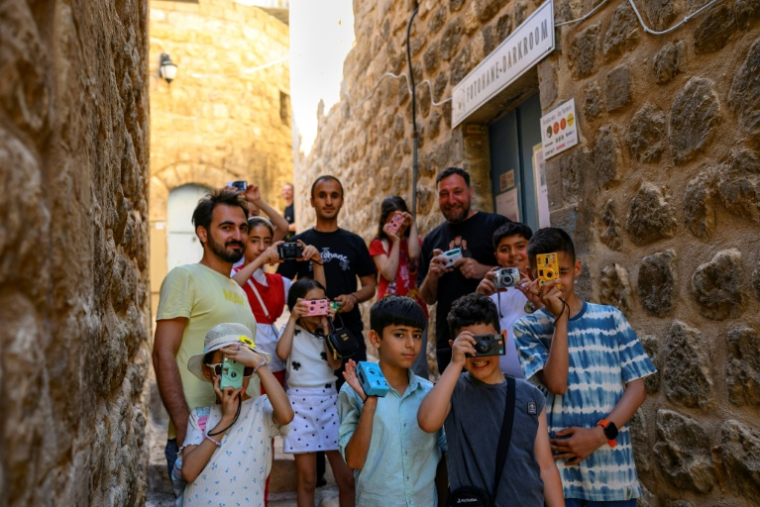 Des enfants développent des pellicules photographiques avec leurs éducateurs et les photographes Serbest Salih (G) et Amar Kilic (3e à droite), lors d'un atelier organisé dans le cadre du projet "Fotohane Darkroom" à Mardin, dans le sud-est de la Turquie, le 13 juin 2026 ( AFP / Yasin AKGUL )